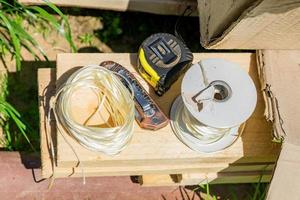 working tools - tape-measure, twine and pocket knife on wooden desk outdoors. Garden maintenance instruments photo