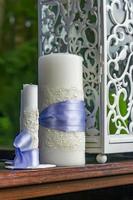 two white candles with purple ribbons on candlestick background photo