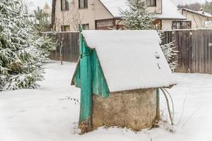 closeup of well covered with snow in countryside photo