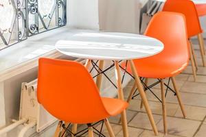 plastic furniture in morden skandi stylr. Orange seats and white table on the cafe photo