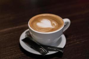 cup of cappuccino with heart on wooden table closeup photo