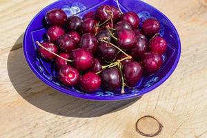 blue plate of ripe sweet cherry on wooden table photo