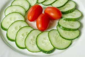 cucumbers and cherry tomatoes on a white plate photo