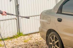 man washing his car under high pressure water outdoors photo