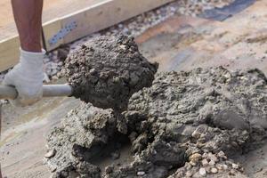 worker mixing concrete and gravel with spade on construction cite photo