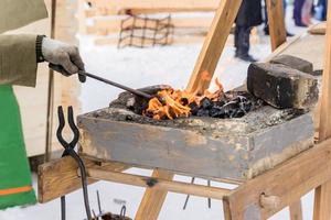 blacksmith manually forging the molten metal on the anvil outdoors photo