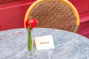 flor única de ranunculus rojo en la mesa con placa reservada foto