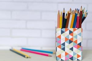 Canister full of colored pencils on table photo