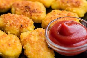 Fried crispy chicken nuggets with ketchup on black plate photo