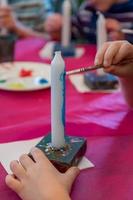 boy colorizes a candle with acrylic paints photo