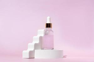 suero facial de colágeno antienvejecimiento en botella de vidrio sobre podio blanco sobre fondo rosa con espacio de copia. concepto de belleza cosmética orgánica natural. maqueta para la marca foto