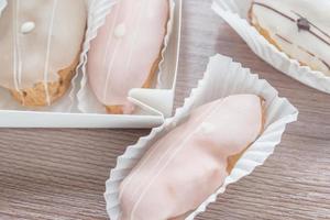 french eclairs in box on wooden table closeup photo