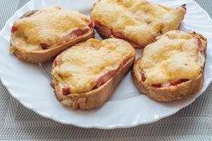 close-up of baked hot sandwiches with cheese and sausage on white plate photo