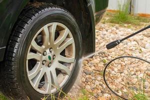 man washing his car under high pressure water outdoors photo