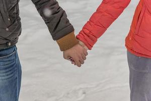 Man and woman holding hands. Young couple walking on winter park photo
