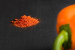 orange bell pepper and paprika powder on black background, copy space for your text photo