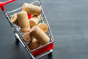 carrito de compras lleno de tapones de corcho usados, concepto sobre fondo de madera foto