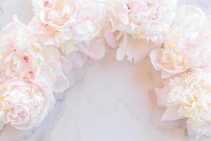 Template for a romantic greeting card with creamy peonies on a white marble background. Blossoming flowers on a white background. pink peonies on a white marble table, flat lay. photo