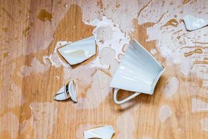 Broken cup with spilled tea on a floor photo