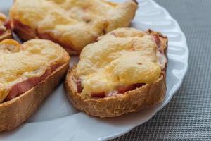 primer plano de sándwiches calientes horneados con queso y salchichas en un plato blanco foto