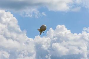 White airship of a soft system with stabilizers and a motor hovers in the sky photo