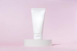 Cream tube with cream branding concept on cocncrete podium on pink background. Cosmetic skincare product blank plastic package. White unbranded lotion, balsam, hand creme, toothpaste mockup. photo