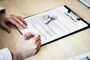 The customer is holding a pen and is reading the housing purchase contract before signing it. photo