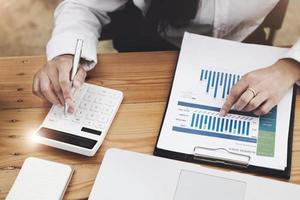 Business woman using calculator to review balance sheet annual  using  document and laptop computer to calculating budget. audit and Check integrity before investment concept. photo