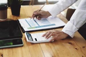 Business woman using calculator to review balance sheet annual  using  document and tablet to calculating budget. audit and Check integrity before investment concept. photo