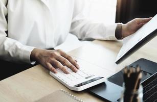 Business woman using calculator to review balance sheet annual  using  document and laptop computer to calculating budget. audit and Check integrity before investment concept. photo