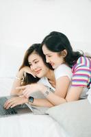 lgbtq, lgbt concept, homosexuality, portrait of two asian women posing happy together and loving each other while playing computer laptop on bed photo