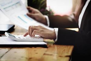 Business woman using calculator to review balance sheet annual  using  document and laptop computer to calculating budget. audit and Check integrity before investment concept. photo