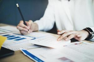 Business woman using calculator to review balance sheet annual  using  document and laptop computer to calculating budget. audit and Check integrity before investment concept. photo