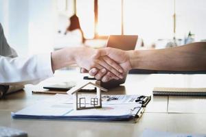 Focus on the congratulatory handshake. The real estate agent agrees to buy the home  to the customer at the agent's office. conceptual agreement. photo