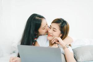 lgbtq, concepto lgbt, homosexualidad, retrato de dos mujeres asiáticas posando felices juntas y amándose mientras juegan a la computadora portátil en la cama foto