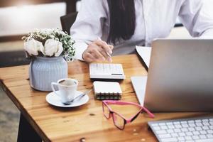 Business woman using calculator to review balance sheet annual  using  document and laptop computer to calculating budget. audit and Check integrity before investment concept. photo