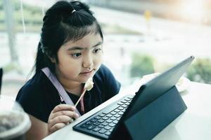 El aprendizaje electrónico, la educación en línea y el distanciamiento social en Internet protegen del concepto de virus covid-19. Aprendizaje electrónico de videoconferencia de estudiantes de niños asiáticos con el maestro en una tableta en casa. foto