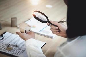 Inspector Concept, a customer is holding a magnifying glass to look at each house model to check the price of a home loan for each model. photo