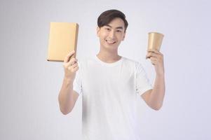 Young asian man holding paper cup and paper box over white background, Save earth concept photo