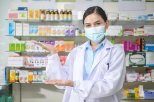 Portrait of female pharmacist wearing face mask in a modern pharmacy drugstore. photo