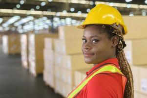 Portrait of young mixed race female worker wearing helmet in modern warehouse storage of retail shop photo