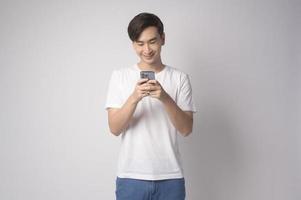 Young asian man using smartphone over white background, technology concept. photo
