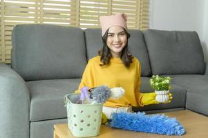 joven mujer feliz con guantes amarillos y quitando el polvo de la mesa en la sala de estar. foto