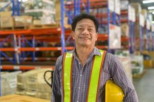 retrato de un trabajador masculino asiático senior con casco en un almacén moderno de una tienda minorista foto