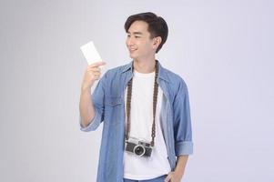Young happy asian tourist man over white background studio, travel and holidays concept. photo