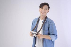 Young happy asian tourist man over white background studio, travel and holidays concept. photo