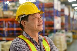 retrato de un trabajador masculino asiático senior con casco en un almacén moderno de una tienda minorista foto