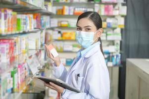 Portrait of female pharmacist wearing face mask in a modern pharmacy drugstore. photo