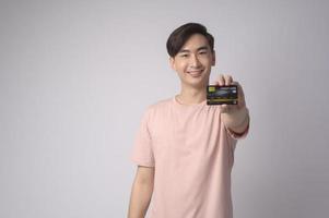 Young asian man holding credit card over white background studio, shopping and finance concept. photo