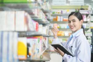 Portrait of female pharmacist using tablet in a modern pharmacy drugstore. photo